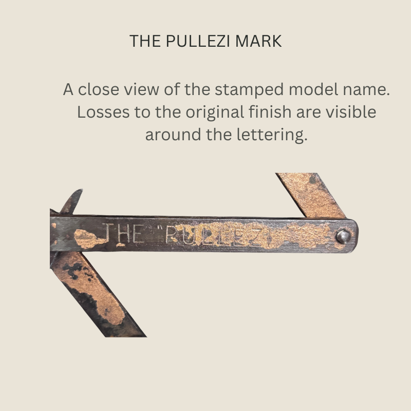 Close-up of the steel linkage on a Heeley Pullezi concertina corkscrew, showing the stamped “THE PULLEZI” name, riveted pivot and extensive losses to the dark surface finish.