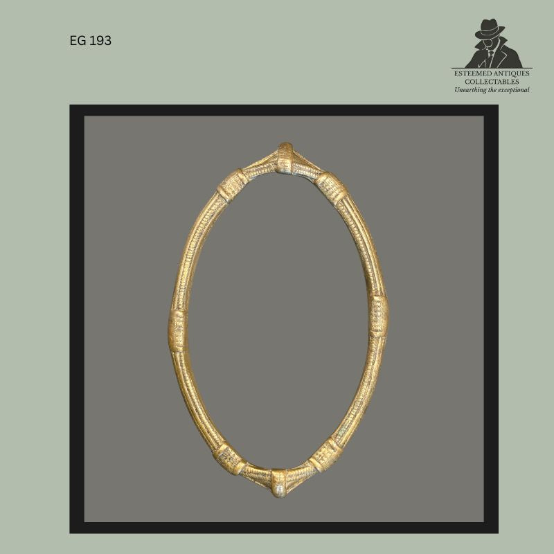 Circular cast brass-bronze anklet currency attributed to the Frafra or Lobi peoples of West Africa, featuring ribbed segmented decoration and pointed terminal elements, photographed from the Egon Guenther Collection.