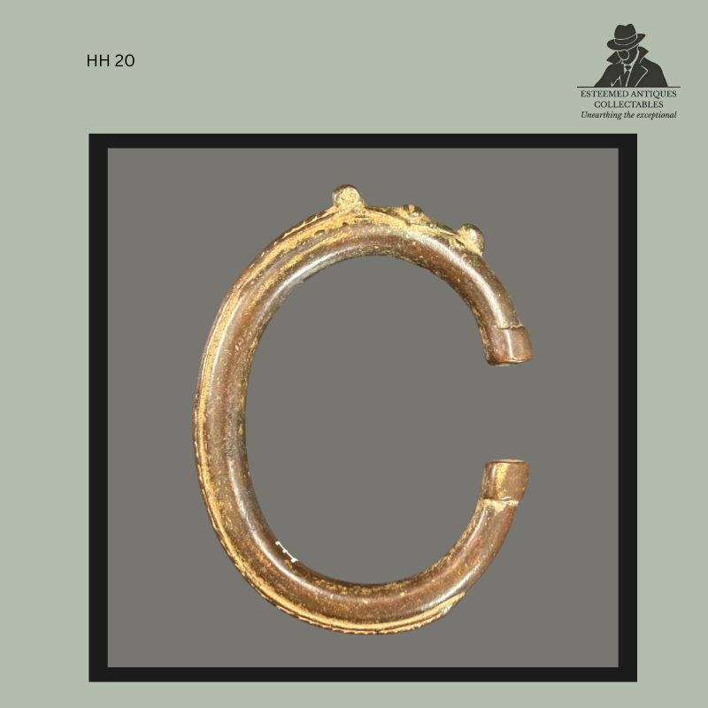 Cast brass open bracelet or arm ring from West Africa, likely Ghana, with rounded hoop form and small integral raised decorative elements along the upper rim. Produced using traditional lost-wax casting techniques and bearing characteristics associated with Akan metalworking traditions. Formerly in the Hans Himmelheber Collection.