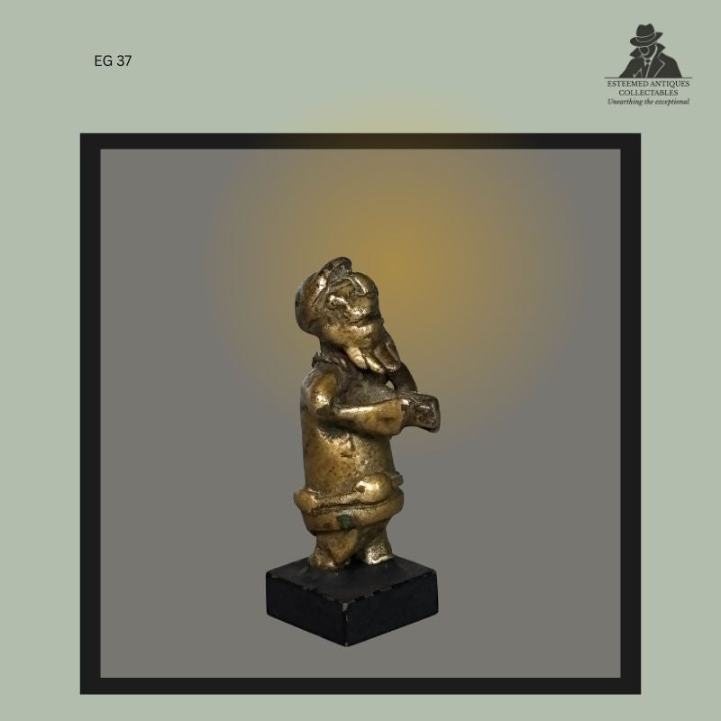 Side view of an Akan brass goldweight depicting a standing human figure with pronounced facial features, cast using the lost-wax technique in Ghana, from the Egon Guenther Collection.