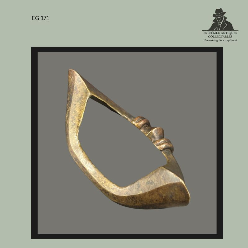 Close view of a West African cast brass anklet currency showing accumulated patina, surface wear, and polished contact areas from prolonged use. The lost-wax cast ornament features a triangular open form with moulded collar decoration and evidence of age consistent with historic personal adornment and prestige currency traditions.