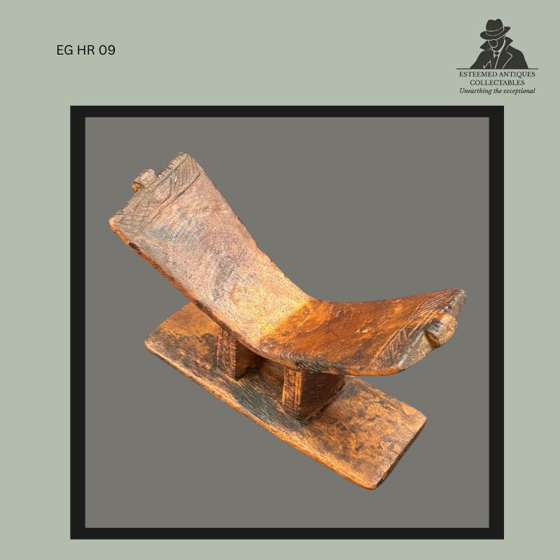 Kuba carved wooden headrest from the Democratic Republic of the Congo, formed from a rectangular base with twin vertical supports rising to a curved neck platform with incised geometric decoration and a dark honey-brown aged surface, from the Egon Guenther Collection.