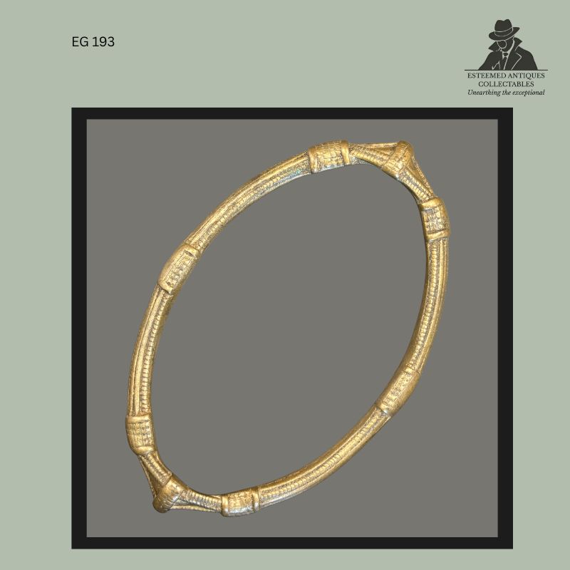 Cast brass-bronze anklet currency from the Frafra or Lobi cultural regions of West Africa, featuring a circular open-form construction with raised segmented decorative bands and worn surface patina, photographed from the Egon Guenther Collection.