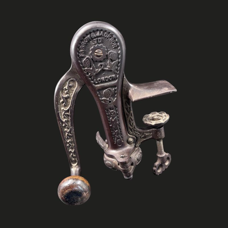 Farrow & Jackson Ltd London cast-iron counter-mounted bar corkscrew, showing the ornate lever mechanism, wooden handle, bottle support and bench clamp, England, c.1900–1915.