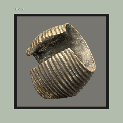 Fragmentary African ceramic vessel section with deep horizontal ribbing and curved hand-built form, showing darkened firing surfaces and exposed interior consistent with traditional earthenware production techniques.
