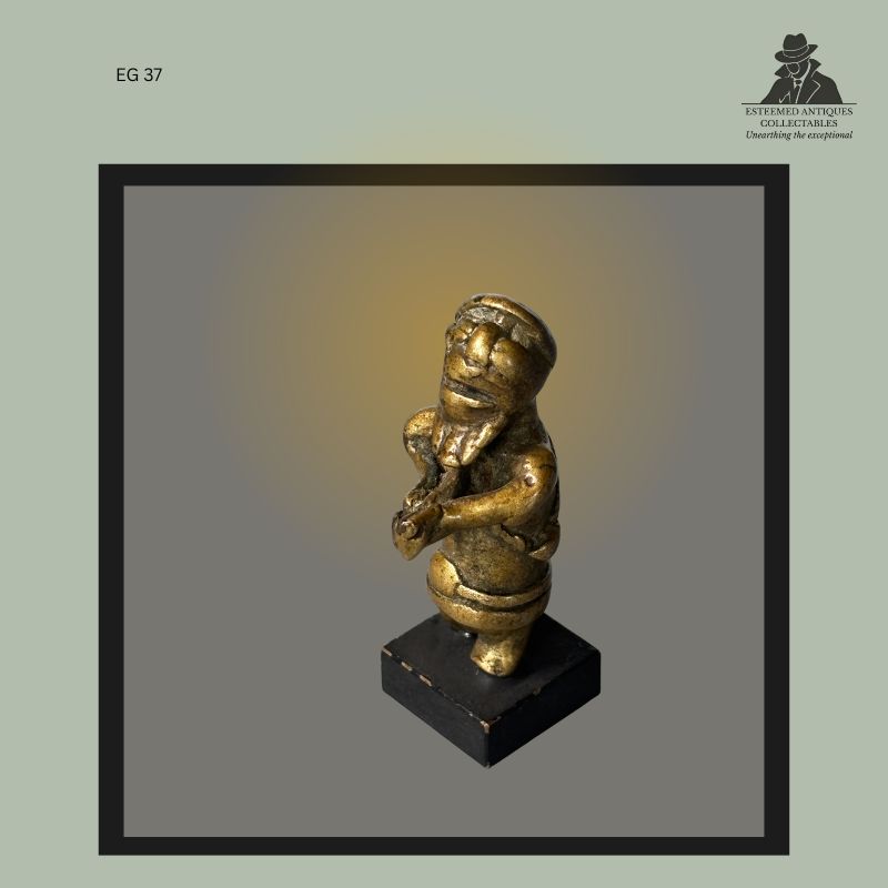 Cast brass Akan gold weight depicting a human figure with clasped hands and pronounced facial features, produced by the lost-wax casting method in Ghana, mounted on a modern display base, from the Egon Guenther Collection.