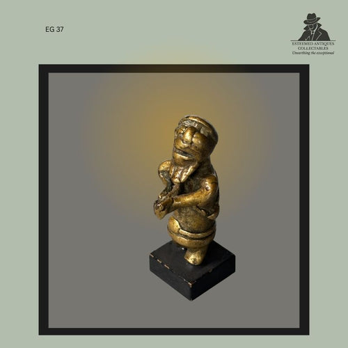 Cast brass Akan gold weight depicting a human figure with clasped hands and pronounced facial features, produced by the lost-wax casting method in Ghana, mounted on a modern display base, from the Egon Guenther Collection.