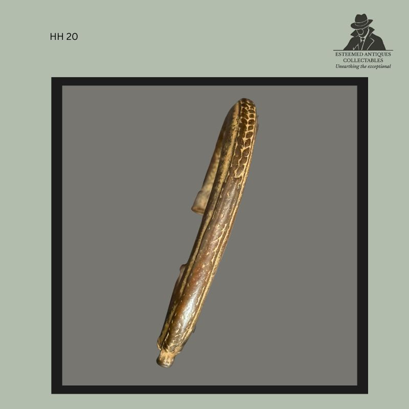 Side profile of a cast brass bracelet attributed to the Akan peoples of Ghana, decorated with a stylised crocodile motif in relief. The bracelet displays an aged patina, surface wear, and oxidation consistent with long-term use and collection history, formerly in the Hans Himmelheber and Egon Guenther collections.