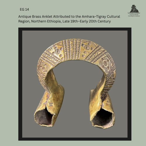 Front view of an antique cast brass anklet attributed to the Amhara–Tigray cultural region of northern Ethiopia, dating from the late 19th to early 20th century, with deeply incised geometric decoration across the arched upper section and flared hollow terminals, from the Egon Guenther Collection.