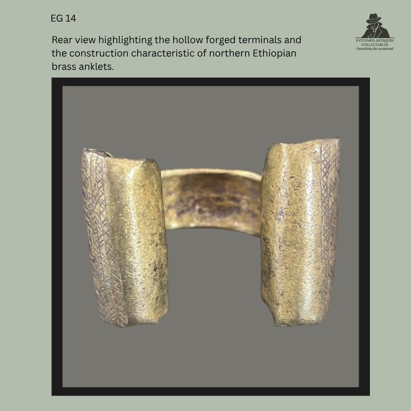 Rear view of a traditional Amhara-Tigray brass anklet from northern Ethiopia, showing the hollow forged terminals with incised geometric decoration and the characteristic open-ended construction, from the Egon Guenther Collection.