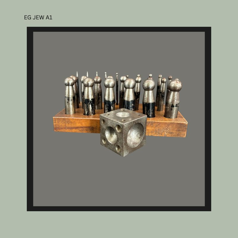 Front view of an antique German jeweller’s doming punch set with machined steel punches arranged in a wooden stand beside a steel dapping block, Used by Egon Guenther when he practiced jewellery in Germany and South Africa.