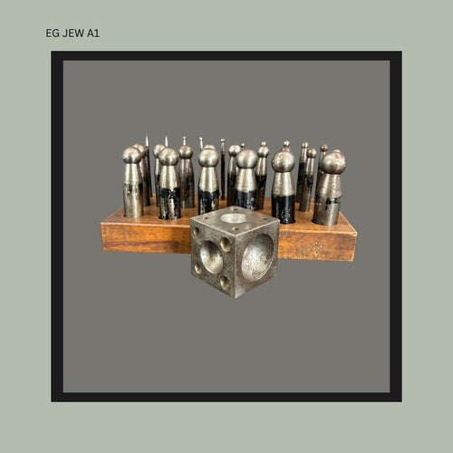 Front view of an antique German jeweller’s doming punch set with machined steel punches arranged in a wooden stand beside a steel dapping block, Used by Egon Guenther when he practiced jewellery in Germany and South Africa.