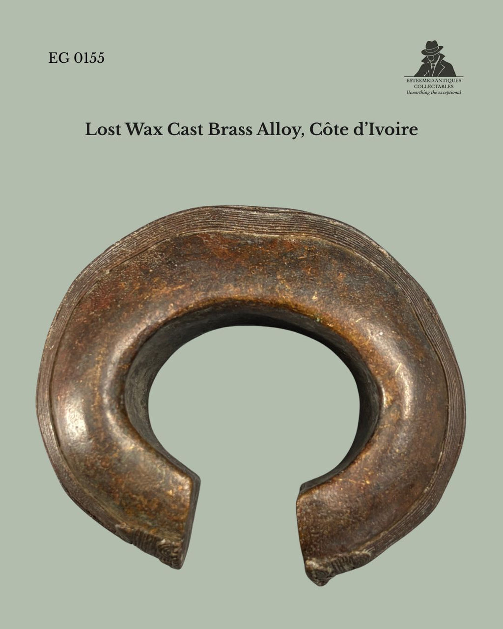 Front view of a Baoulé lost-wax cast brass alloy anklet from Côte d’Ivoire, showing its substantial open-cuff form, rounded hollow-cast construction, and finely incised decoration along the outer rim, from the Egon Guenther Collection.