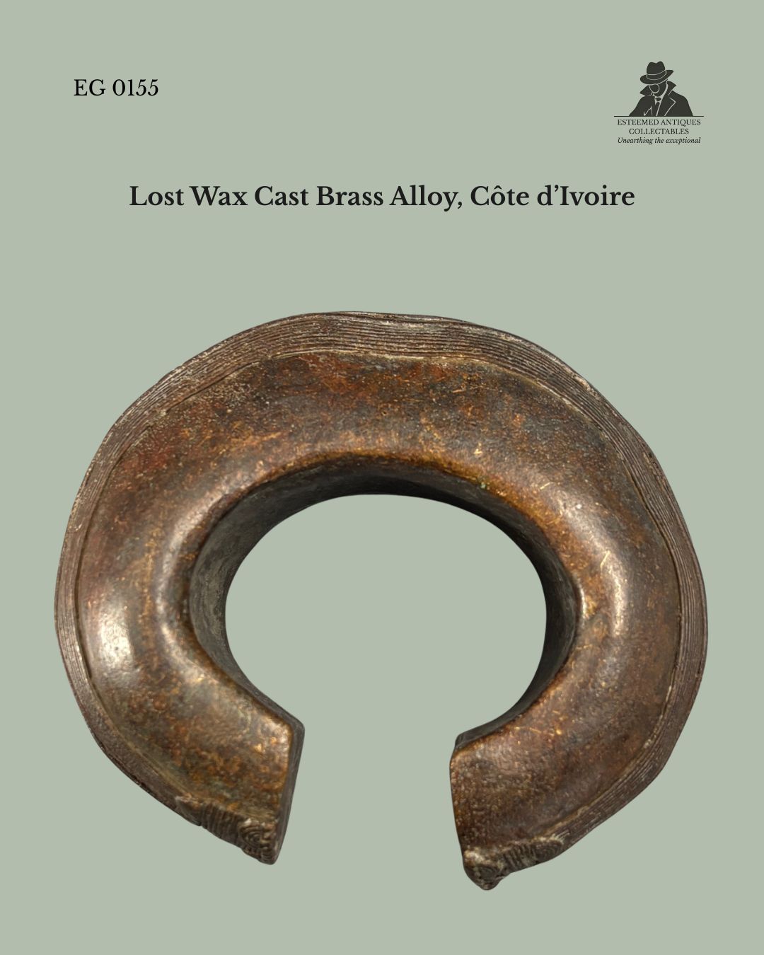 Front view of a Baoulé lost-wax cast brass alloy anklet from Côte d’Ivoire, showing its substantial open-cuff form, rounded hollow-cast construction, and finely incised decoration along the outer rim, from the Egon Guenther Collection.