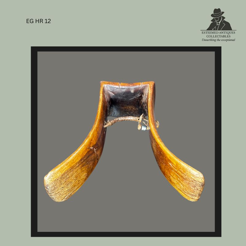 Interior view of an East African carved wooden tribal headrest showing the underside of the sleep platform, curved supporting columns, polished surface wear, dark patina from prolonged use, and a fibre-bound repair securing the structural supports.