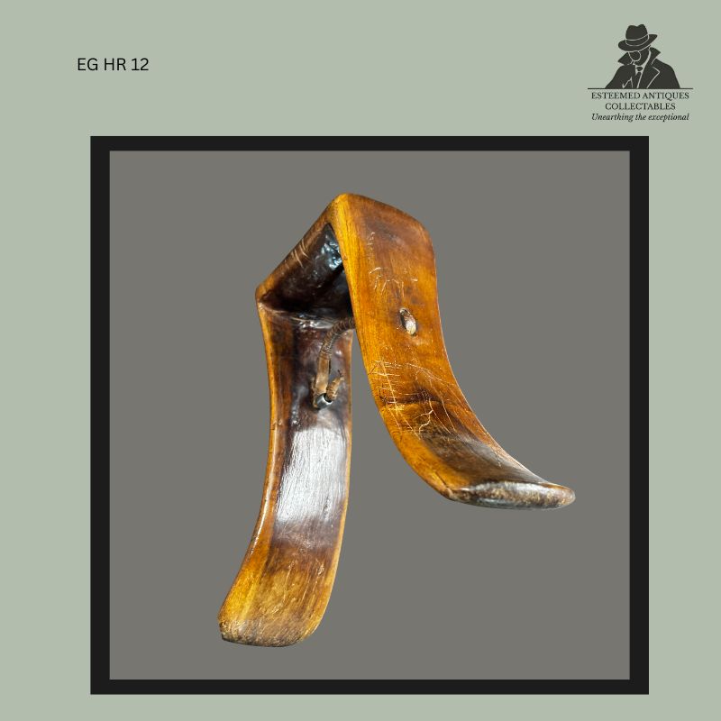 Interior view of an East African carved wooden headrest showing the hollowed underside, bent support form, suspension cord attachment, and polished surface wear from use. Ethnographic headrest carved from a single piece of wood, from the Egon Guenther Collection.