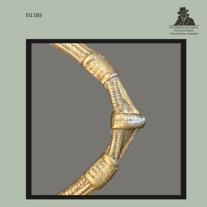 Detail view of a Frafra or Lobi cast brass-bronze anklet currency from West Africa, showing ribbed surface decoration, curved form, and projecting central element with worn patinated surface, from the Egon Guenther family collection.