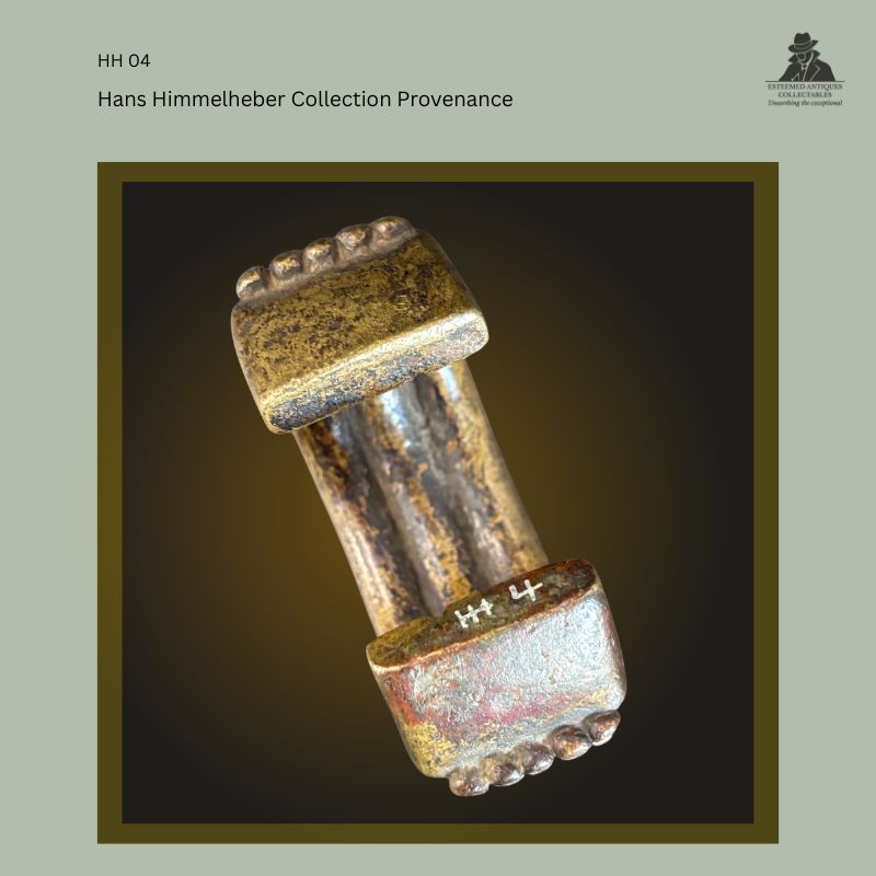 Interior view of a cast brass West African manilla currency bracelet showing the collector's inventory mark HH 4, with characteristic terminal projections and provenance from the Hans Himmelheber Collection.