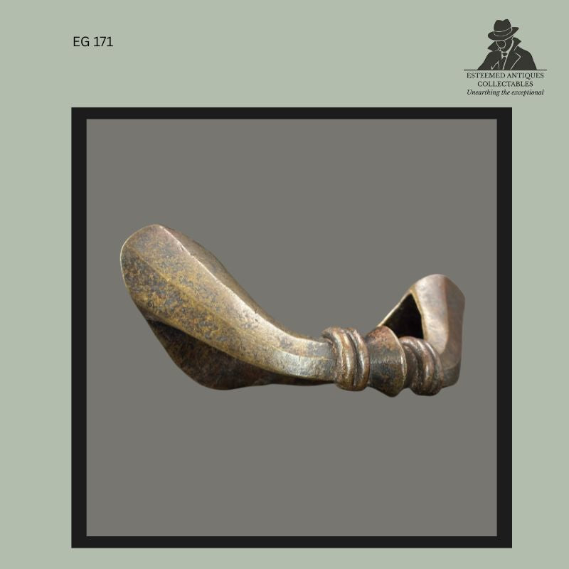 Cast bronze Senufo currency anklet from Côte d’Ivoire, West Africa, featuring a broad flattened terminal, twisted body section, and ringed collar detail, produced by lost-wax casting and formerly used as personal adornment and a prestige currency object; Egon Guenther family collection.