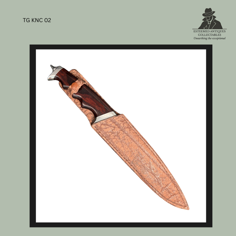 South African handmade custom hunting knife partially sheathed in a tan textured leather scabbard, with a polished dark hardwood finger-grooved handle, metal guard, and sculpted pommel visible above the sheath.