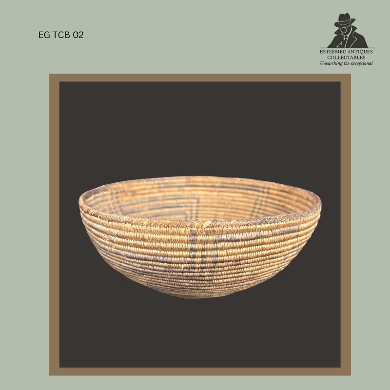Low-profile Southern Tswana hand-coiled fibre bowl with finely stitched natural grass construction and subtle dark geometric patterning, viewed from the side, from the Egon Guenther Collection.