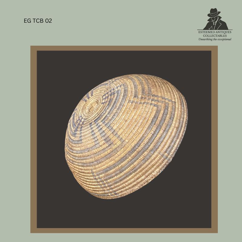 op view of a Southern Tswana handwoven lidded basket showing the domed cover with concentric coiled weaving and subtle geometric dyed fibre decoration, traditionally constructed from natural grass fibres, from the Egon Guenther Collection.