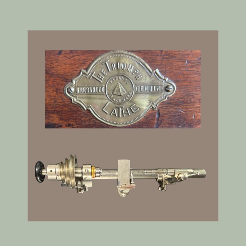 Brass maker’s plaque reading “The Triumph Lathe” with Pyramid trademark above a precision watchmaker’s lathe headstock and slide attachment, an early horology engineering component associated with small-scale clock and watchmaking workshop equipment.