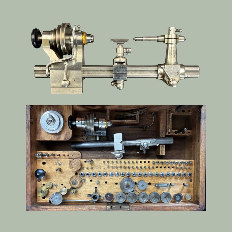 Triumph precision watchmaker’s lathe with polished metal headstock, tailstock, tool rest, collets, chucks, and specialist horology accessories displayed in a fitted wooden case for fine clockmaking and mechanical instrument work, early 20th century.