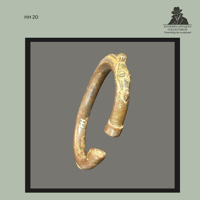 Cast brass open bracelet from West Africa with a stylised anthropomorphic terminal depicting a human face, the opposite end finished with a rounded knop. The bracelet displays a warm brown-gold patina and bears a Himmelheber inventory mark, from the Hans Himmelheber and Egon Guenther collections.