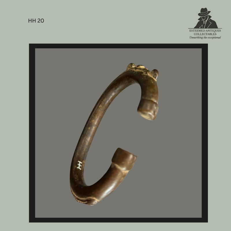 West African cast brass bracelet with stylised crocodile-head terminals, formed as an open circular arm ring with smooth patinated surface and Hans Himmelheber inventory mark, collected in the Ghana region and later preserved in the Egon Guenther Collection.