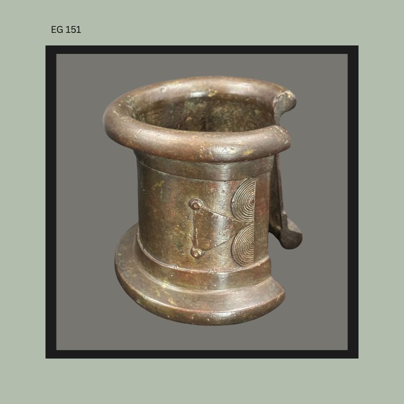 West African cast bronze anklet or bracelet with heavy circular rim, geometric incised decoration, and projecting clasp element, photographed from the side against a neutral background, Egon Guenther Collection.