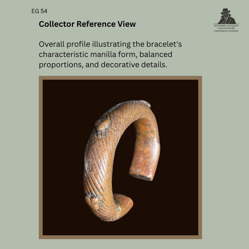 Profile view of a West African cast copper manilla bracelet showing its characteristic open circular form, incised linear decoration, rounded terminal details, and balanced proportions, from the Egon Guenther Collection.