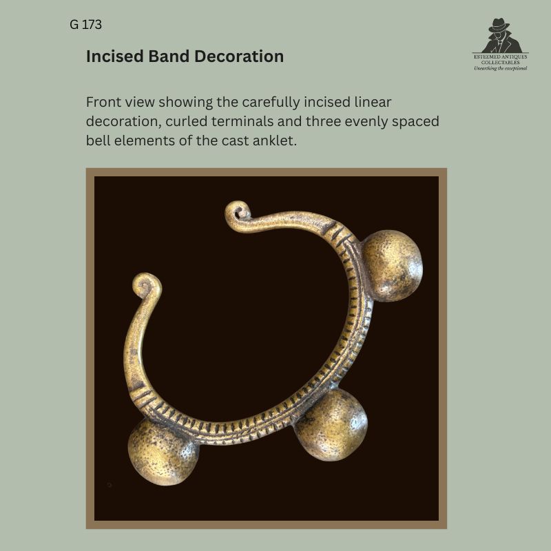 Front view of West African cast prestige anklet showing incised linear band decoration, curled terminals and three evenly spaced spherical bell elements, Egon Guenther Collection.