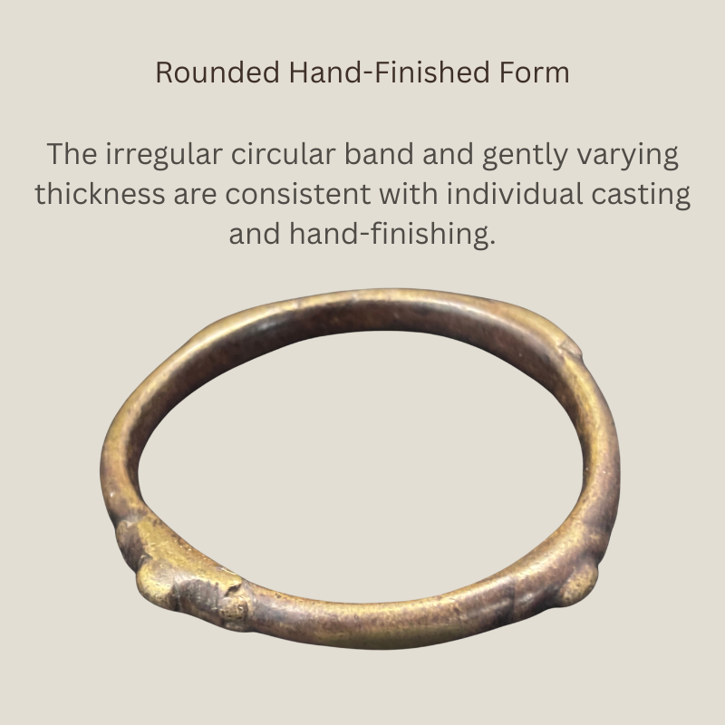 Oblique view of a West African copper-alloy bangle showing its irregular circular band, gently varying thickness and hand-finished cast surface.