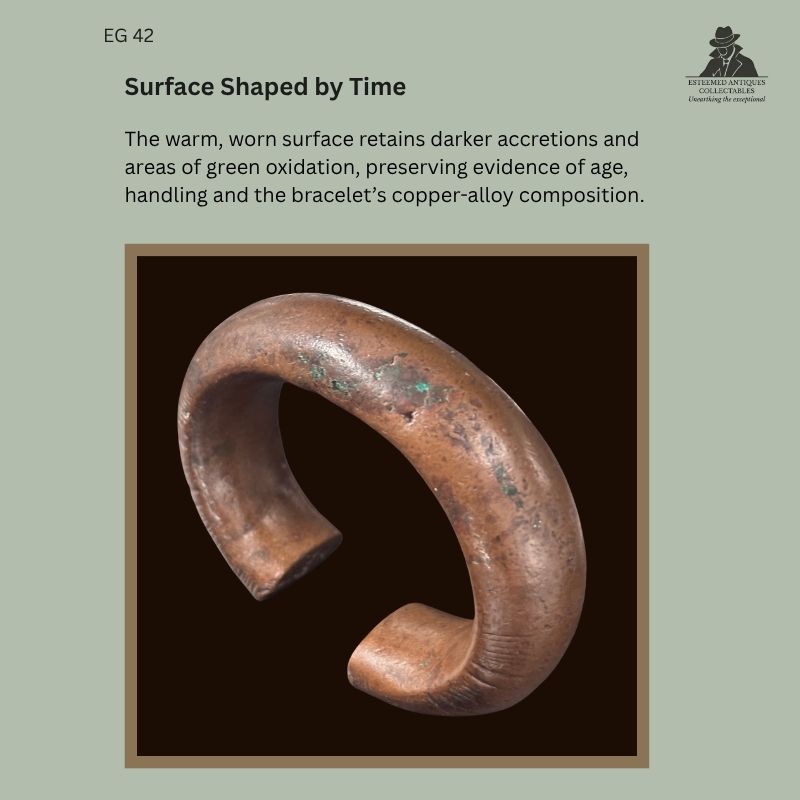 Catalogue panel showing the worn copper-alloy surface of West African penannular bracelet EG 42, probably Senufo, with dark accretions, green oxidation and broad flattened terminals.
